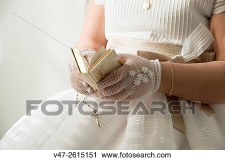 Stock Image - Girl reading the bible on the day of his first communion. Fotosearch