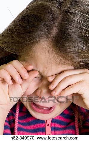 Stock Image - Girl who cries and rubs his eyes with both hands. Fotosearch