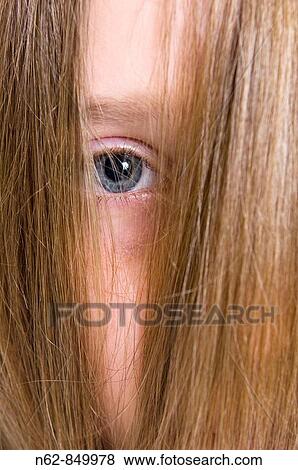 Stock Photo - Girls hidden by their blond hair smooth, leaving only one blue eye to see. Fotosearch