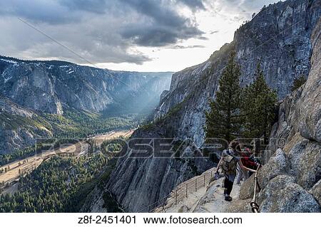 Stock Image - Group of hikers going down to Yosemite Point with the amazing view of the valley and the sunset, California, USA.. Fotosearch