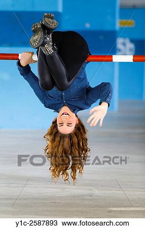 Stock Image - Hanging inverted on parking ramp young woman. Fotosearch