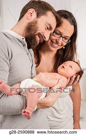 Happy and proud parents holding their newborn baby boy and smiling View Large Photo Image Stock Photo - Happy and proud parents holding their newborn baby boy and smiling. Fotosearch