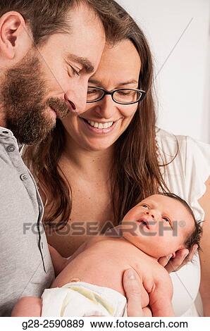 Happy and proud parents holding their newborn baby boy and smiling View Large Photo Image Stock Photo - Happy and proud parents holding their newborn baby boy and smiling. Fotosearch