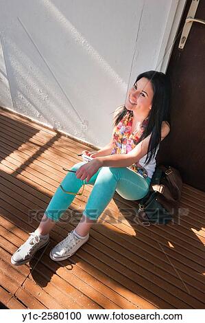 Stock Image - Happy student young woman sitting on floor. Fotosearch