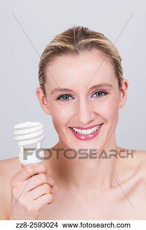 Happy young woman holding energy saving light bulb. View Large Photo Image Picture - Happy young woman holding energy saving light bulb.. Fotosearch