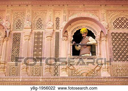 Stock Image - Indian man lookng throw the window, Mehrangarh Fort, Jodhpur, Rajasthan, India.. Fotosearch
