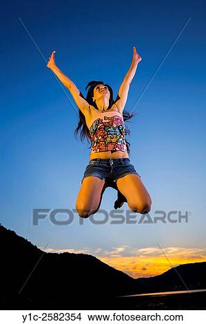 Picture - Jumping woman in sunset. Fotosearch