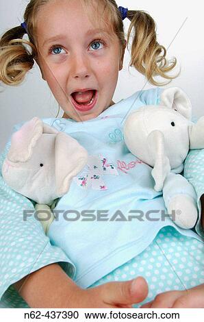 Stock Image - Little girl with pigtails bottom view has puppet under the arms and makes funny faces. Fotosearch
