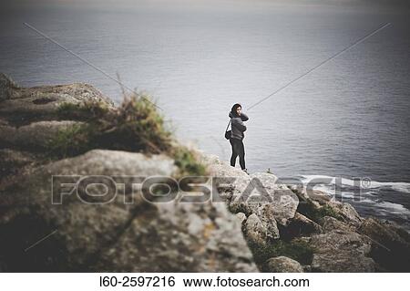 Stock Photograph - Lonely girl in lighthouse Cape Finisterre. La Coruña province, Galicia, Spain.. Fotosearch