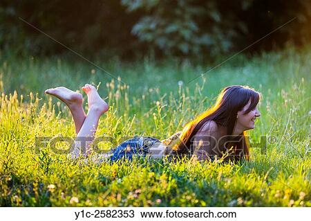 Lying happy barefeet in grass young woman warm light View Large Photo Image Stock Image - Lying happy barefeet in grass young woman warm light. Fotosearch
