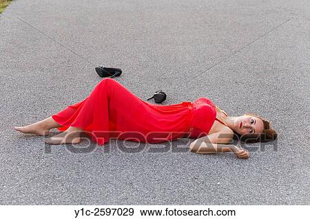 Lying on road in long Red dress young woman detached shoes View Large Photo Image Stock Photo - Lying on road in long Red dress young woman detached shoes. Fotosearch