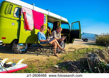 man and young woman sit and read next to camper with surfboards with view at the coast of Portugal View Large Photo Image Stock Photograph - man and young woman sit and read next to camper with surfboards with view at the coast of Portugal. Fotosearch