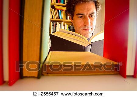 Man consulting a book of a private library in an interior of a house. View Large Photo Image Stock Photo - Man consulting a book of a private library in an interior of a house.. Fotosearch