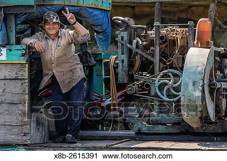 Man on river boat on the Mekong River Delta at Cai Be, Vietnam. View Large Photo Image Stock Image - Man on river boat on the Mekong River Delta at Cai Be, Vietnam.. Fotosearch