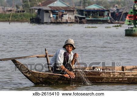 Stock Image - Man pulling fishing net in small sampan in Chau Doc, Mekong River Delta, Vietnam.. Fotosearch