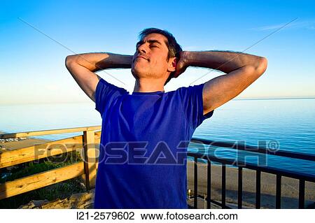 Man resting behind a railing near the sea, he is wearing a blue t-shirt. View Large Photo Image Stock Image - Man resting behind a railing near the sea, he is wearing a blue t-shirt.. Fotosearch