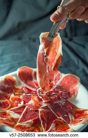 Man´s hand holding a piece of Iberian ham using tongs. View Large Photo Image Stock Image - Man´s hand holding a piece of Iberian ham using tongs.. Fotosearch
