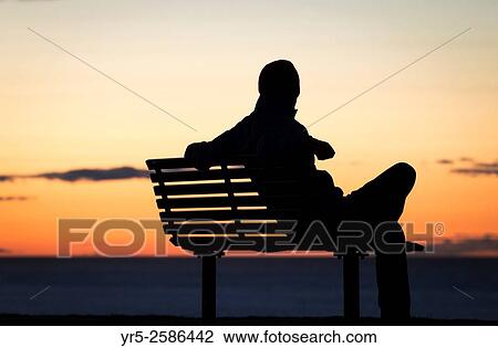 Man sitting on seat overlooking North Sea at sunset at Whitby, North Yorkshire, England, United Kingdom. View Large Photo Image Stock Image - Man sitting on seat overlooking North Sea at sunset at Whitby, North Yorkshire, England, United Kingdom.. Fotosearch