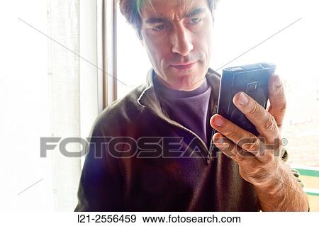 Stock Photo - Man with casual clothes using a mobile phone, consulting his smartphone.. Fotosearch