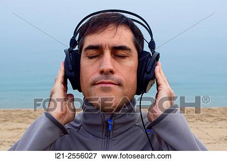 Stock Photo - Man with headphones listening to music on the beach, outdoor.. Fotosearch