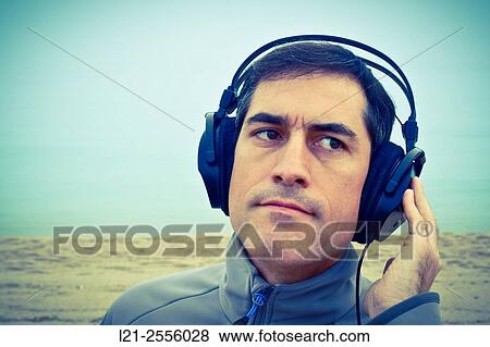 Man with headphones listening to music on the beach, outdoor. View Large Photo Image Stock Photo - Man with headphones listening to music on the beach, outdoor.. Fotosearch
