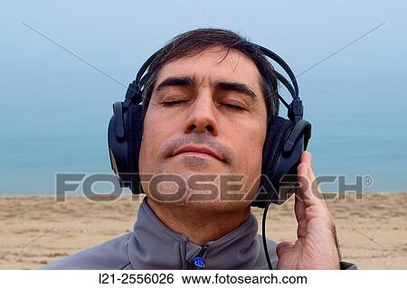 Man with headphones listening to music on the beach, outdoor. View Large Photo Image Stock Photograph - Man with headphones listening to music on the beach, outdoor.. Fotosearch