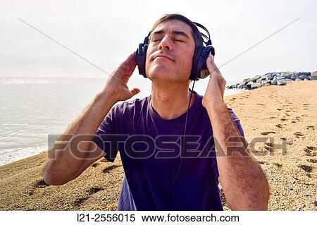 Man with headphones listening to music on a beach, near the sea. View Large Photo Image Stock Photography - Man with headphones listening to music on a beach, near the sea.. Fotosearch