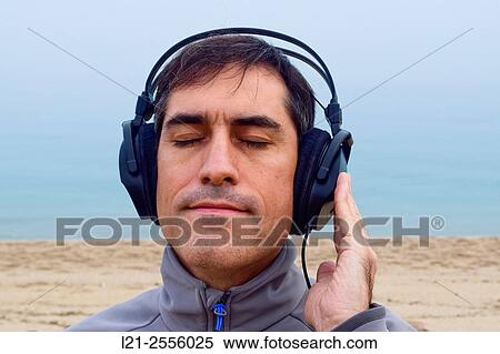 Man with headphones listening to music on the beach, outdoor. View Large Photo Image Stock Photography - Man with headphones listening to music on the beach, outdoor.. Fotosearch