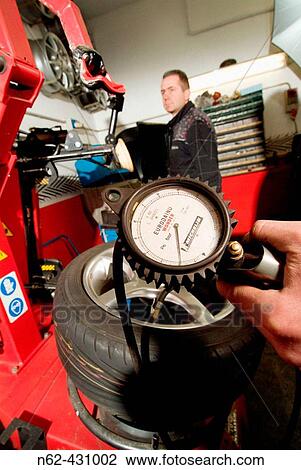 Manometer hand held by the tire repairer while controlling the pressure of a tire in his workshop on the bottom of his colleague observes View Large Photo Image Stock Image - Manometer hand held by the tire repairer while controlling the pressure of a tire in his workshop on the bottom of his colleague observes. Fotosearch