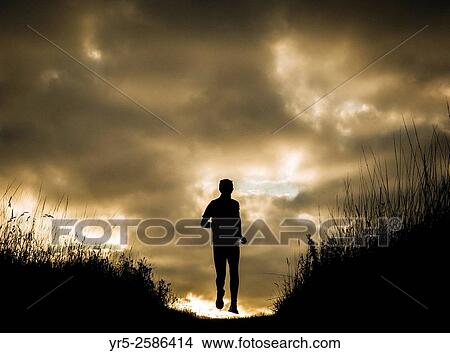 Mature man running over hill at sunrise. Cowpen Woodland Park, Billingham, England, United Kingdom. View Large Photo Image Picture - Mature man running over hill at sunrise. Cowpen Woodland Park, Billingham, England, United Kingdom.. Fotosearch