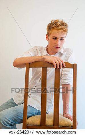 Melancholic young man sitting on a chair. View Large Photo Image Stock Photo - Melancholic young man sitting on a chair.. Fotosearch