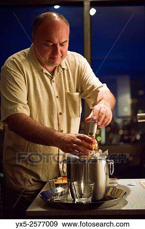Middle aged man opening a bottle of wine in a hotel room. View Large Photo Image Stock Photo - Middle aged man opening a bottle of wine in a hotel room.. Fotosearch