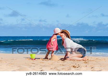 Stock Image - Mother and daughter kissing on the beach, Kauai island.. Fotosearch