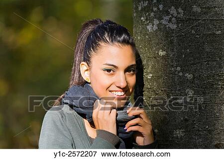 Stock Photo - Mulatto happy portrait teen girl in forest inclined on tree. Fotosearch