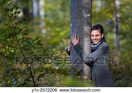 Stock Photograph - Mulatto teen girl in forest embracing tree. Fotosearch