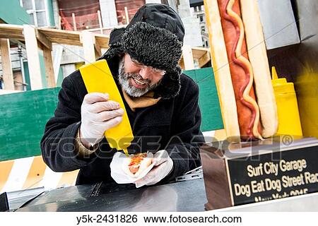 Stock Photograph - New York, USA. Egyptian immigrant to the united States selling Hot Dogs & Pretsels from his mobile stand, Down Town Manhattan.. Fotosearch
