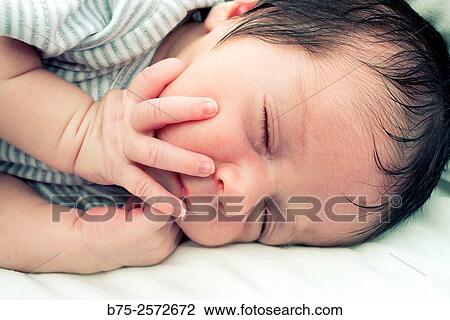 Newborn baby girl sleeping peacefully in her cradle with her hands on the face. View Large Photo Image Stock Image - Newborn baby girl sleeping peacefully in her cradle with her hands on the face.. Fotosearch
