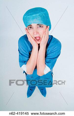 Nurse with blue uniform top view puts her hands around her face while the mouth is wide open to express despair View Large Photo Image Stock Photography - Nurse with blue uniform top view puts her hands around her face while the mouth is wide open to express despair. Fotosearch