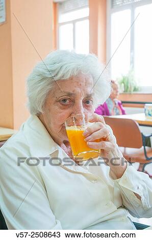 Old woman drinking orange juice and looking at the camera. View Large Photo Image Stock Image - Old woman drinking orange juice and looking at the camera.. Fotosearch