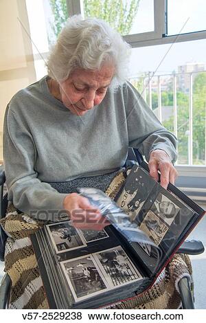 Old woman leafing through a family photo album in a nursing home. View Large Photo Image Stock Photo - Old woman leafing through a family photo album in a nursing home.. Fotosearch
