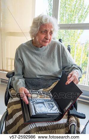 Old woman with a family photo album in a nursing home. View Large Photo Image Stock Photograph - Old woman with a family photo album in a nursing home.. Fotosearch