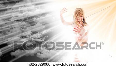 Stock Photograph - On the left a dark sky is evil, on the right a woman angel with her energy powers the sun with its rays resurrects the good.. Fotosearch