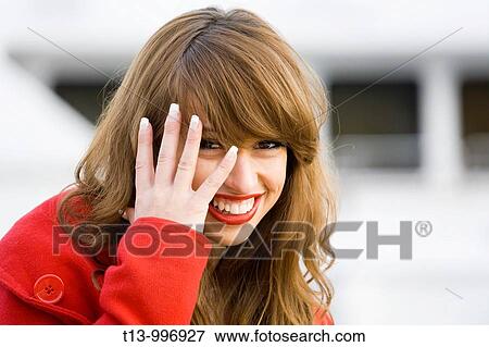 Stock Photo - Peeking and smiling through fingers pretty woman portrait. Fotosearch