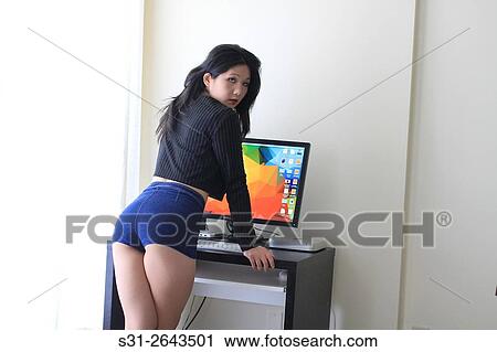 Stock Image - portrait of a beautiful young asian girl from canada posing in front of a monitor.. Fotosearch