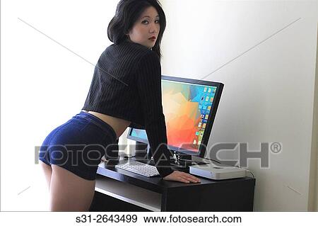 Stock Photo - portrait of a beautiful young asian girl from canada posing in front of a monitor.. Fotosearch