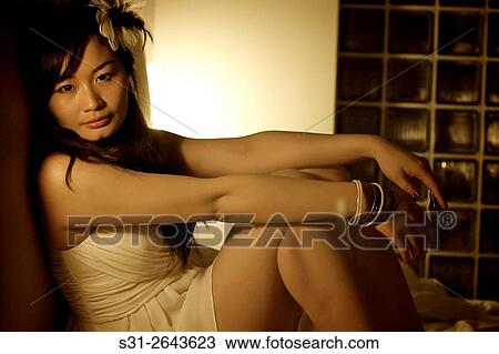 Stock Image - portrait of a beautiful young Chinese girl playing on bed.. Fotosearch