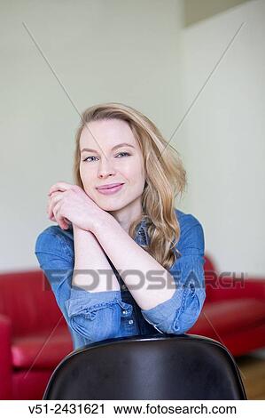 Stock Image - Portrait of a blonde woman smiling at camera in the living room. Fotosearch