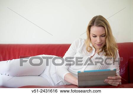 Portrait of a pretty blonde woman with a digital tablet on the couch View Large Photo Image Stock Photograph - Portrait of a pretty blonde woman with a digital tablet on the couch. Fotosearch