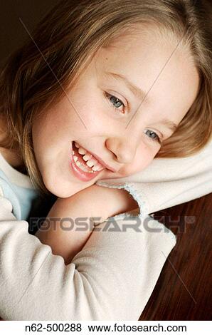 Stock Photo - Portrait of a smiling little girl resting her head on her arms crossed. Fotosearch