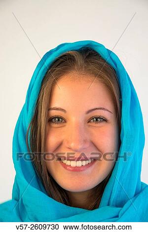 Stock Image - Portrait of blonde young woman wearing turquoise shawl, smiling and looking at the camera.. Fotosearch